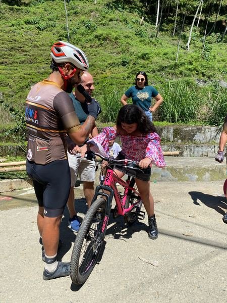 Integrante de Fundacion Tourmalet ayudando a nina con su bicicleta en actividad comunitaria